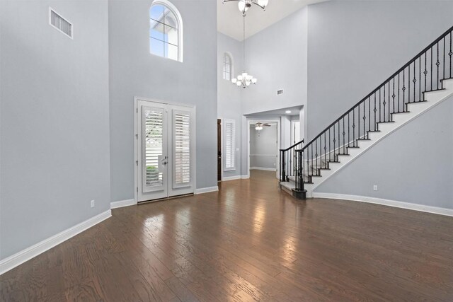 foyer entrance featuring a healthy amount of sunlight, stairway, ceiling fan with notable chandelier, and wood-type flooring