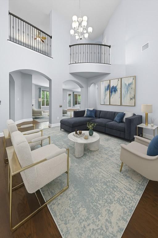 2015 Colina Cv, Cedar Park, TX 78613 - living room featuring arched walkways, a high ceiling, wood finished floors, and a chandelier