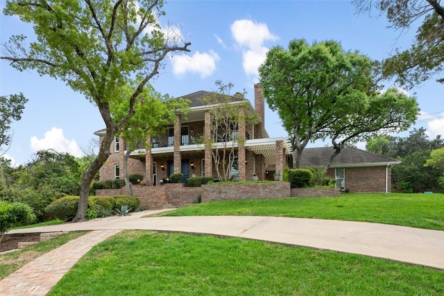 6605 Canon Wren Dr, Austin, TX 78746 - view of front of home featuring a balcony, a front lawn, brick siding, and a chimney