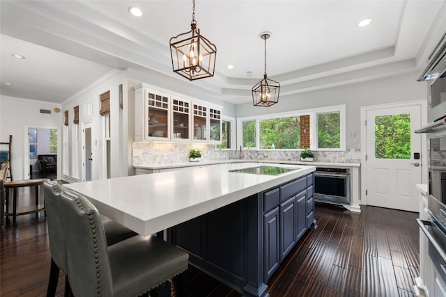 6605 Canon Wren Dr, Austin, TX 78746 - kitchen featuring oven, a raised ceiling, black electric cooktop, light countertops, and tasteful backsplash