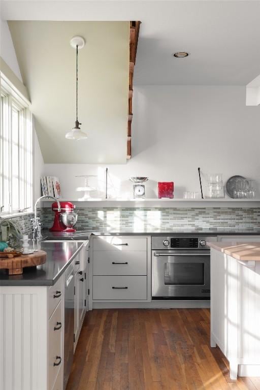 1313 W 9th 1/2 St, Austin, TX 78703 - kitchen featuring appliances with stainless steel finishes, white cabinetry, decorative backsplash, dark wood-style flooring, and vaulted ceiling