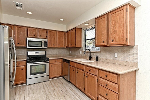 5003 Wing Rd, Austin, TX 78749 - kitchen featuring stainless steel appliances, a sink, brown cabinets, backsplash, and recessed lighting