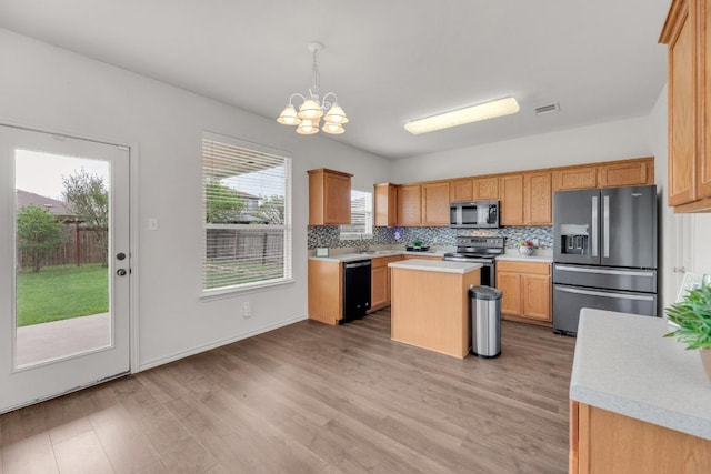 13605 Lyndon B Johnson St, Manor, TX 78653 - kitchen with appliances with stainless steel finishes, a chandelier, light countertops, light wood-style flooring, and decorative backsplash