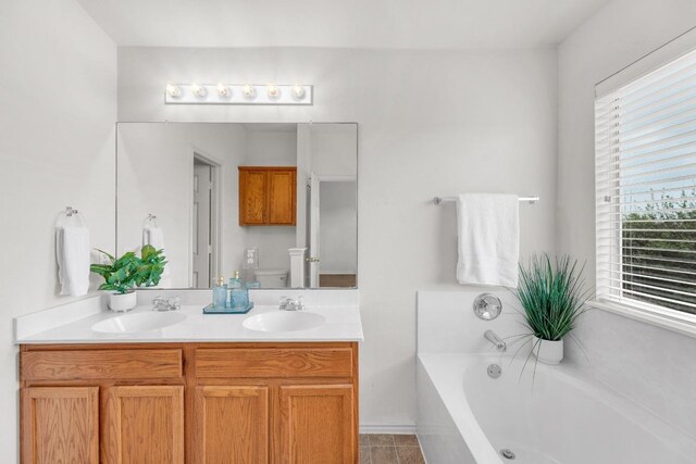 13605 Lyndon B Johnson St, Manor, TX 78653 - full bathroom with a garden tub, double vanity, toilet, and tile patterned floors