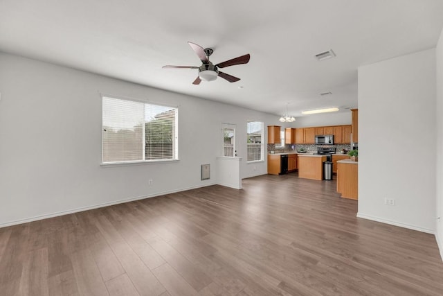 13605 Lyndon B Johnson St, Manor, TX 78653 - unfurnished living room featuring a chandelier, a ceiling fan, dark wood-style flooring, and baseboards