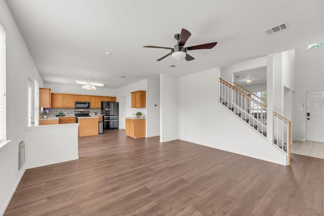 13605 Lyndon B Johnson St, Manor, TX 78653 - unfurnished living room featuring stairs, a ceiling fan, wood finished floors, a chandelier, and baseboards