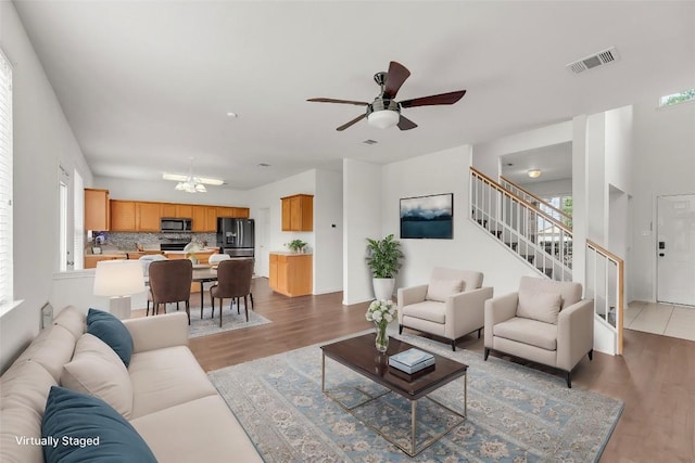 13605 Lyndon B Johnson St, Manor, TX 78653 - living room with ceiling fan, wood finished floors, stairway, and a chandelier