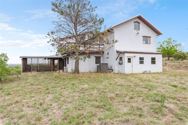 back of house with a sunroom, a yard, stucco siding, and central AC unit
