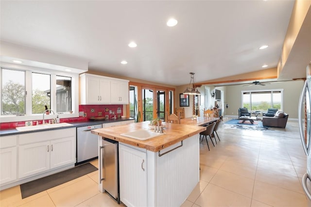 kitchen with a sink, butcher block countertops, white cabinets, and dishwasher