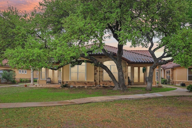 view of front of home featuring a front yard, stucco siding, and a tiled roof