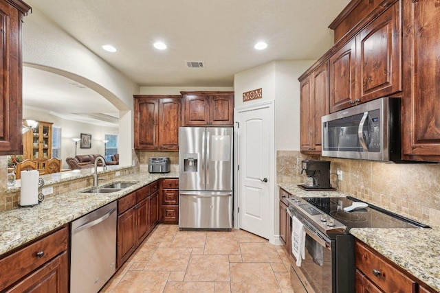 2004 American Dr Unit 1, Lago Vista, TX 78645 - kitchen featuring appliances with stainless steel finishes, a sink, tasteful backsplash, light stone counters, and stone tile floors