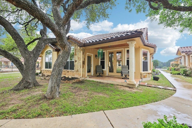 2004 American Dr Unit 1, Lago Vista, TX 78645 - view of front facade with a tile roof, french doors, stucco siding, and a front lawn