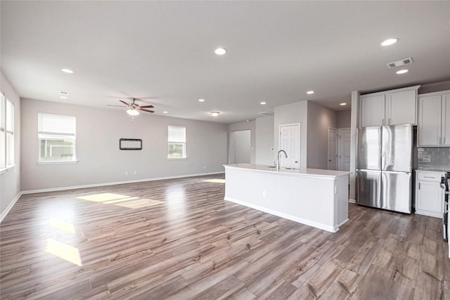 12103 Tolson Dr, Manor, TX 78653 - kitchen featuring freestanding refrigerator, recessed lighting, a ceiling fan, wood finished floors, and an island with sink