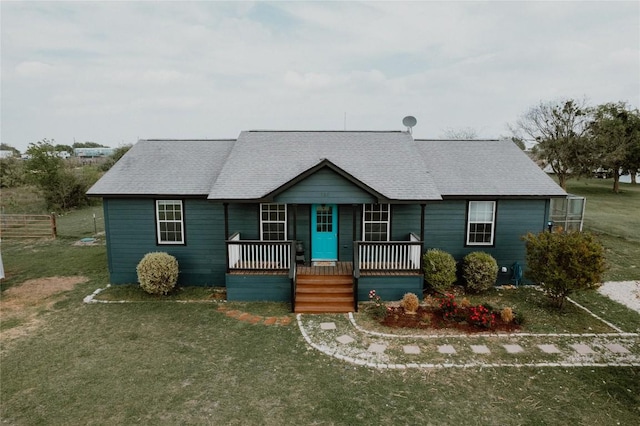 ranch-style house with covered porch, fence, a front lawn, and roof with shingles