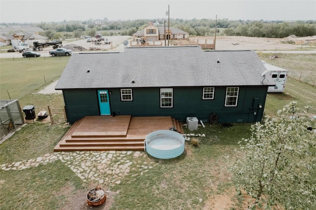 back of property featuring central AC unit, a deck, and roof with shingles