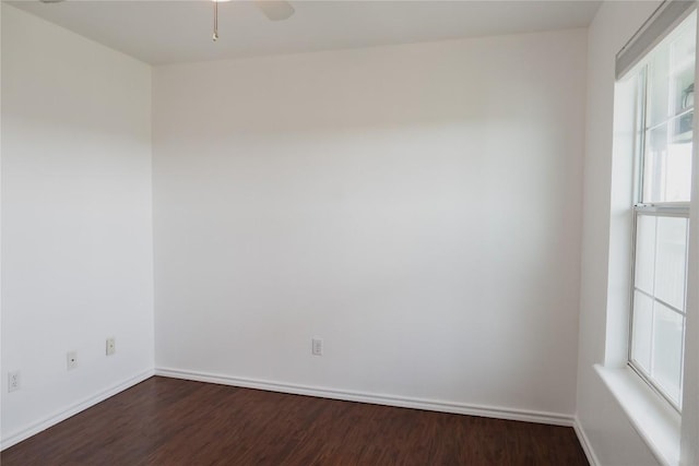 empty room featuring dark wood-style floors, baseboards, and ceiling fan