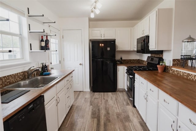 kitchen featuring white cabinets, wooden counters, a sink, and black appliances