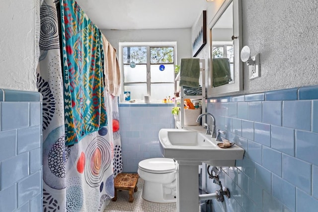 1403 Ashwood Rd, Austin, TX 78722 - full bath featuring tile walls, tile patterned flooring, a shower with shower curtain, and a wainscoted wall