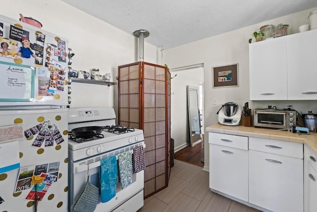 1403 Ashwood Rd, Austin, TX 78722 - kitchen featuring white appliances, tile countertops, white cabinets, and a textured ceiling