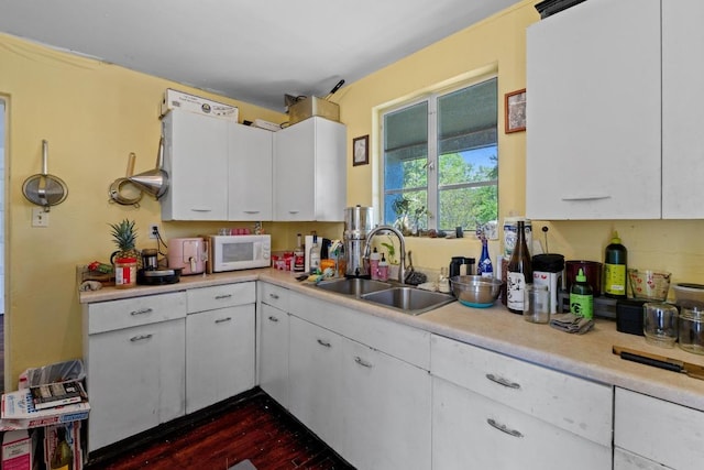 1403 Ashwood Rd, Austin, TX 78722 - kitchen with white microwave, light countertops, white cabinets, and dark wood-style flooring