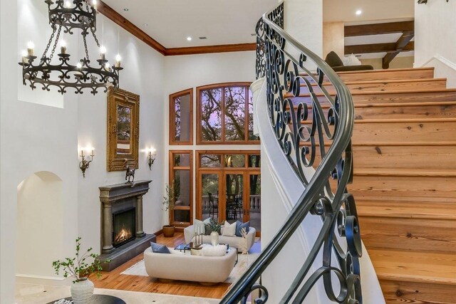 4646 Rockcliff Rd, Austin, TX 78746 - stairs with a towering ceiling, a chandelier, ornamental molding, a lit fireplace, and wood finished floors