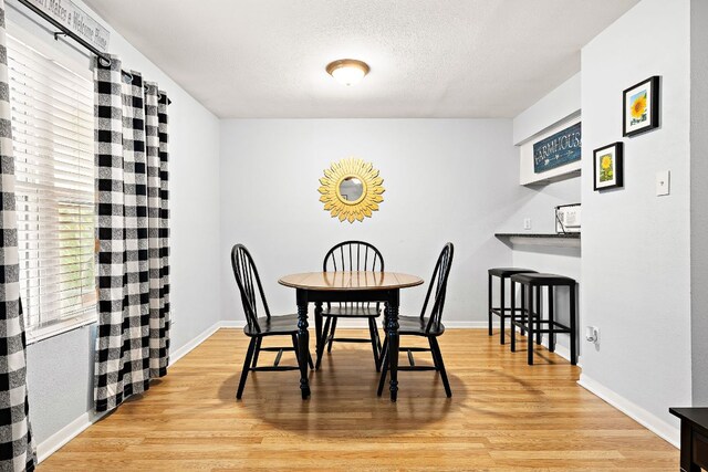 2450 Ashdale Dr Unit B-211, Austin, TX 78757 - dining area with baseboards, a textured ceiling, and light wood-style flooring