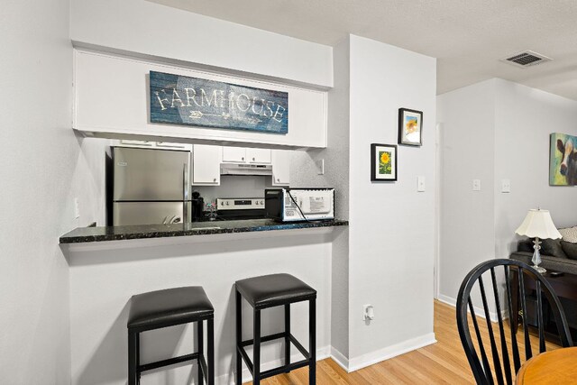 2450 Ashdale Dr Unit B-211, Austin, TX 78757 - kitchen featuring visible vents, white cabinets, under cabinet range hood, stainless steel appliances, and light wood-style flooring