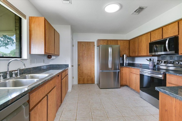 1710 County Road 128, Burnet, TX 78611 - kitchen featuring stainless steel appliances, brown cabinets, dark countertops, and light tile patterned floors