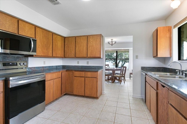 1710 County Road 128, Burnet, TX 78611 - kitchen with appliances with stainless steel finishes, brown cabinetry, dark countertops, and light tile patterned flooring