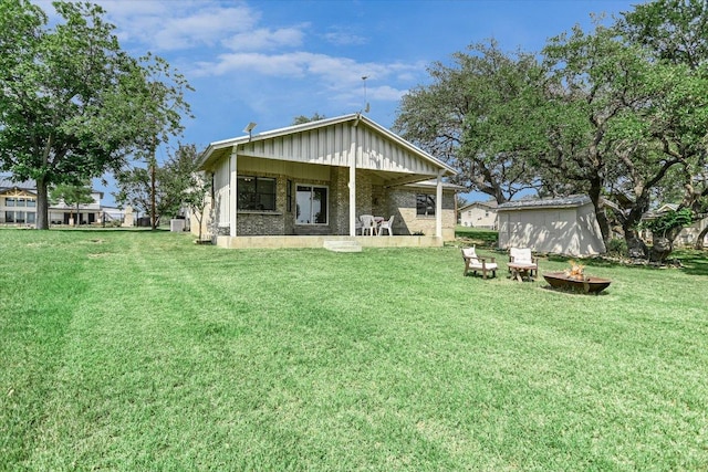 1710 County Road 128, Burnet, TX 78611 - rear view of house featuring an outdoor fire pit, a lawn, and board and batten siding