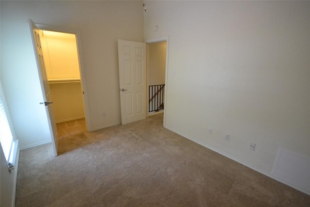 unfurnished bedroom with a spacious closet, carpet, and baseboards