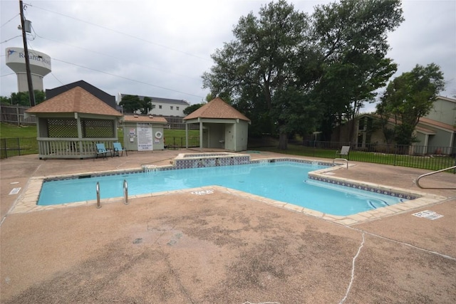 pool featuring fence, an outdoor structure, and a patio area