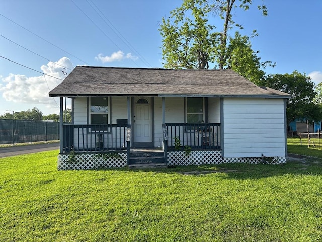 view of front of property with fence, covered porch, a shingled roof, and a front lawn