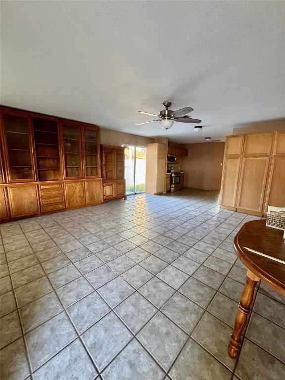 700 Lago Vista St, San Marcos, TX 78666 - unfurnished living room featuring light tile patterned floors, a textured ceiling, and a ceiling fan