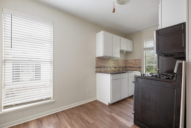 5300 Guadalupe St Unit 6202, Austin, TX 78751 - kitchen with wood finished floors, range with gas cooktop, white cabinetry, a textured ceiling, and dark countertops