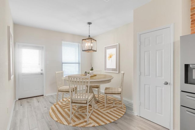 dining area with baseboards, light wood finished floors, and an inviting chandelier