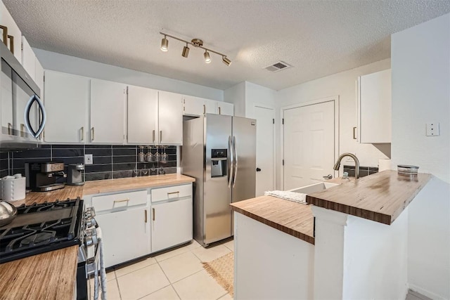 14487 Robert I Walker Blvd, Austin, TX 78728 - kitchen featuring stainless steel appliances, butcher block countertops, tasteful backsplash, a peninsula, and light tile patterned flooring