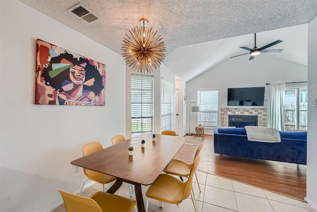 14487 Robert I Walker Blvd, Austin, TX 78728 - dining space featuring a tiled fireplace, light tile patterned flooring, a ceiling fan, a chandelier, and lofted ceiling