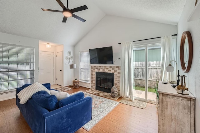 14487 Robert I Walker Blvd, Austin, TX 78728 - living area featuring a ceiling fan, vaulted ceiling, wood finished floors, a brick fireplace, and a textured ceiling