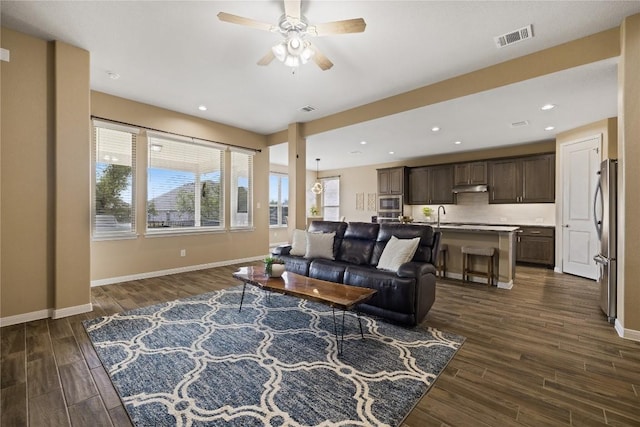 living room featuring dark wood finished floors, visible vents, ceiling fan, and baseboards