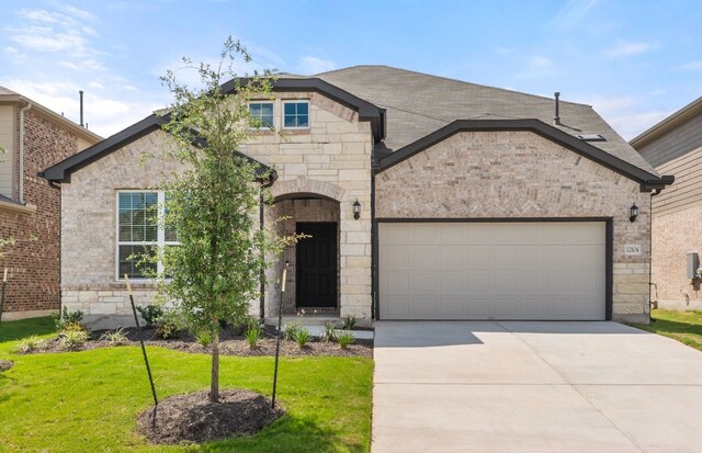 12104 Bacalar Bnd, Manor, TX 78653 - french provincial home with a front lawn, stone siding, an attached garage, and driveway