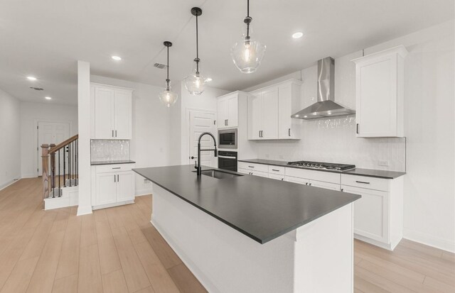 12104 Bacalar Bnd, Manor, TX 78653 - kitchen with wall chimney exhaust hood, dark countertops, stainless steel appliances, decorative backsplash, and light wood-style floors