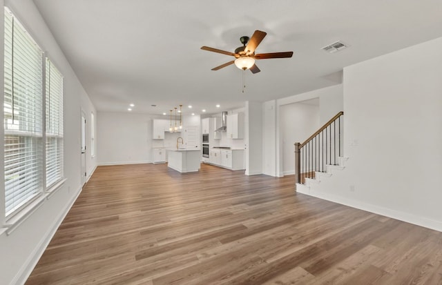16724 Santiaguillo Trce, Manor, TX 78653 - unfurnished living room with recessed lighting, ceiling fan, light wood-style floors, and stairway