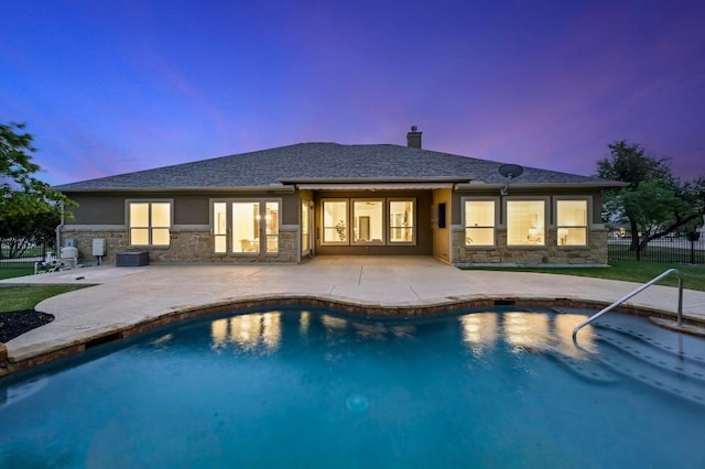 2204 High Lonesome, Leander, TX 78641 - back of property at dusk with stone siding, a patio, a chimney, and stucco siding
