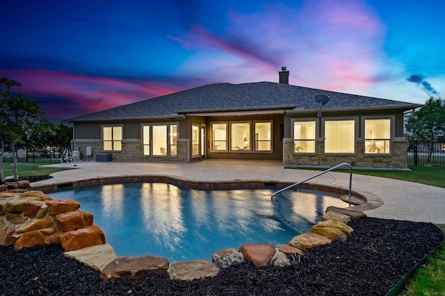 2204 High Lonesome, Leander, TX 78641 - back of house at dusk featuring stone siding, a patio, a chimney, and a shingled roof