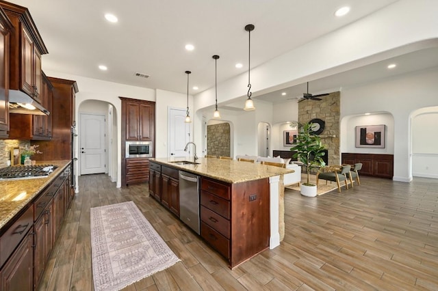 kitchen featuring arched walkways, stainless steel appliances, a ceiling fan, open floor plan, and under cabinet range hood