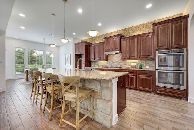 2204 High Lonesome, Leander, TX 78641 - kitchen featuring stainless steel appliances, a sink, light wood-type flooring, backsplash, and a kitchen bar