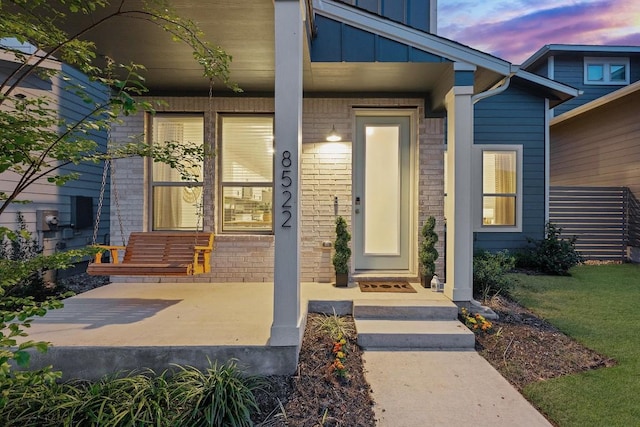 8522 Leroi Dr, Austin, TX 78744 - exterior entry at dusk featuring board and batten siding, a porch, and brick siding