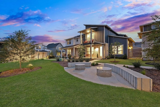 8522 Leroi Dr, Austin, TX 78744 - back of house at dusk featuring a balcony, a patio area, a yard, and board and batten siding