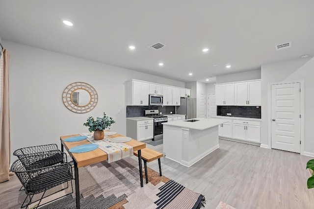 8522 Leroi Dr, Austin, TX 78744 - kitchen featuring stainless steel appliances, tasteful backsplash, light countertops, white cabinets, and a kitchen island with sink